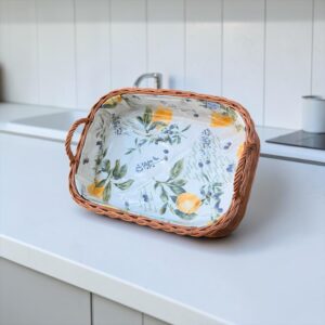 Handgeflochtenes Bukora® Serviertablett aus Naturweide in Schrägansicht mit zwei Griffen und Zitronen- und Olivendesign.