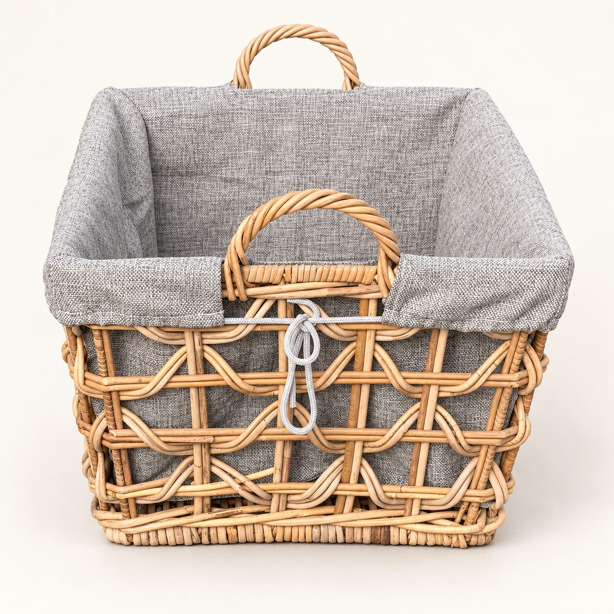 Kurze Seite des Rattankorbs Biggy rechteckig mit offenem Flechtmuster, grauem Stoffinlett und Rattan-Tragegriff.