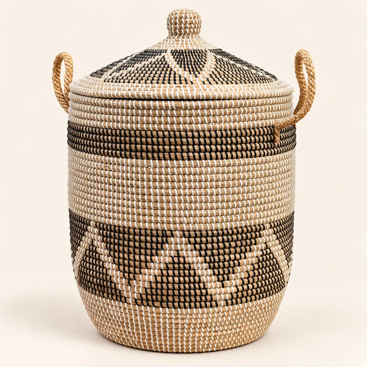 Runder Seegras-Wäschekorb im Afrika-Design in Schwarz-Weiß/Natur mit geschlossenem Deckel, geflochtenem Knauf und zwei seitlichen Griffen.